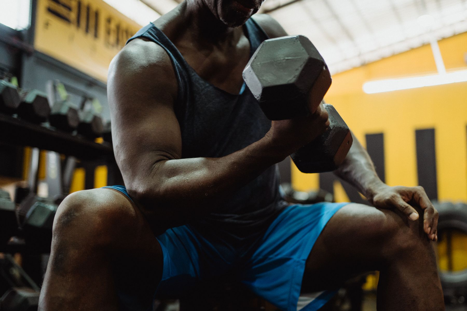 Spor salonunda dambılla tek kol çalışan kişi